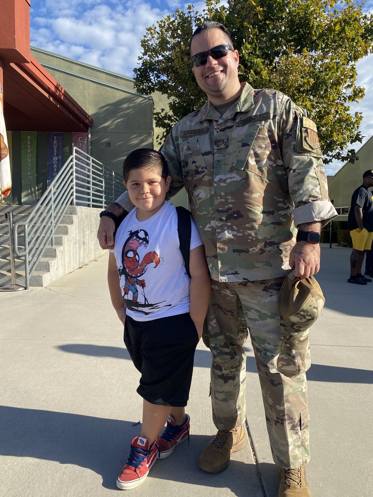 student with military dad in front of tree